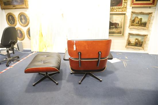 A Charles Eames cherrywood and black leather lounge chair with matching stool, made by Vitra, chair W.2ft 8in. D.2ft 8in. H.2ft 8.5in.